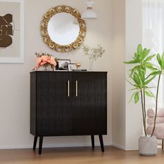 a black cabinet with a mirror and potted plant in the corner next to it