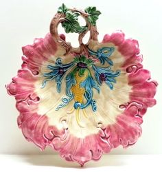 a decorative pink and white dish with an ornate design on the front, sitting on a white surface