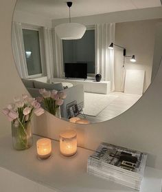 a mirror that is on top of a table with flowers and candles in front of it