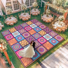 a bride and groom standing on a colorful rug in the middle of an outdoor venue