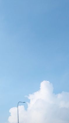 an airplane is flying high in the sky above some buildings and cars on a street