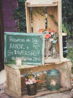 an old wooden box with flowers on it and a chalkboard sign in the middle