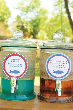 two jars filled with liquid sitting on top of a wooden table next to each other