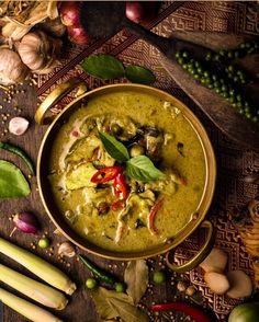 a bowl filled with green curry next to some vegetables and other things on the table