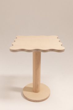 a small wooden table with an oval base and scalloped edges on the top