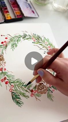 someone is painting a christmas wreath with watercolors