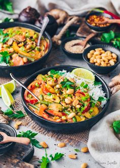 several bowls filled with food and garnished with cilantro, lime wedges