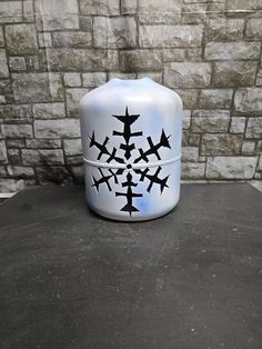 a white vase sitting on top of a table next to a brick wall with planes painted on it