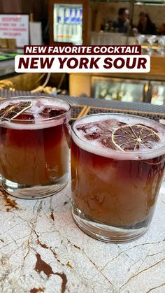 two glasses filled with liquid sitting next to each other on top of a marble counter