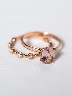 two gold rings with a pink diamond on each one and beaded around the band