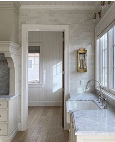 a kitchen with white cabinets and marble counter tops, along with an open door leading to another room