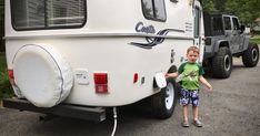 a little boy standing next to a white trailer