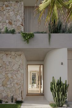 an entrance to a modern home with cactus and plants in the foreground, on a sunny day