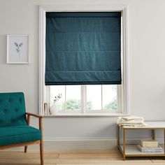 a blue chair sitting in front of a window next to a green chair and table