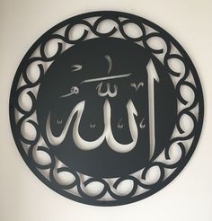 a circular metal sign with an arabic calligraphy in the center on a white wall