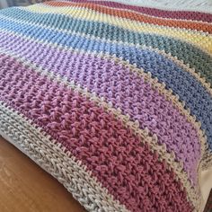 a crocheted blanket sitting on top of a bed next to a wooden floor