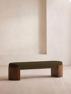 a wooden bench sitting on top of a hard wood floor next to a white wall