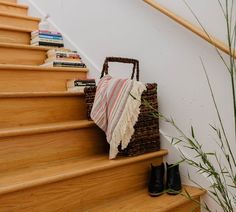 a basket sitting on top of a wooden stair case next to a plant and books