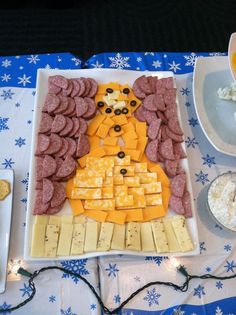 a platter of cheese, meats and crackers on a table with blue snowflakes