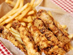 fried chicken and french fries are on a plate with a red checkered table cloth