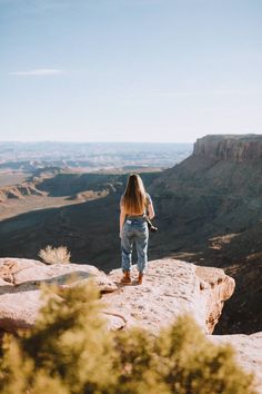 a woman standing on top of a large rock