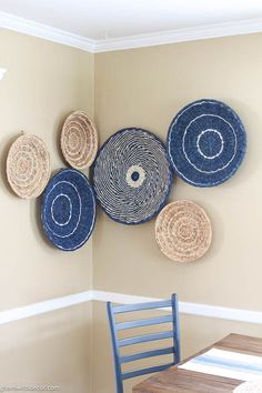 four baskets hanging on the wall above a dining room table with a blue chair next to it