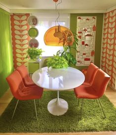 an orange and green dining room with white table, red chairs and potted plants