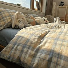 a stuffed animal sitting on top of a bed next to pillows and blankets in front of a window