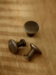 two metal knobs sitting on top of a wooden table