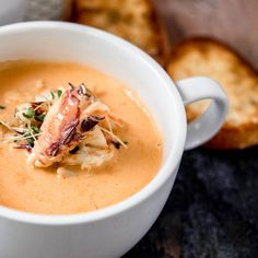 a white bowl filled with soup and garnished with seaweed on top next to slices of bread