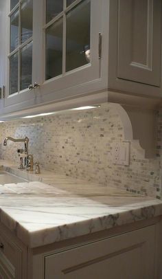 a kitchen with marble counter tops and white cupboards on either side of the sink