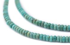 three pieces of turquoise colored beads on a white surface