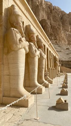 the statues are lined up on the side of the building with ropes in front of them