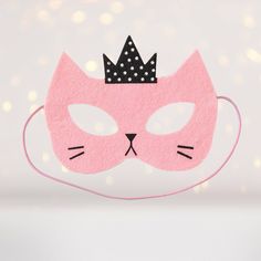 a pink cat mask with a black crown on it's head and polka dots