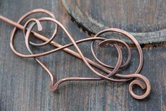 a piece of copper wire sitting on top of a wooden table next to a metal object