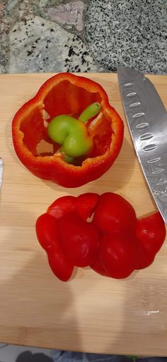 a knife and some red peppers on a cutting board