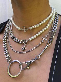 a woman wearing three different necklaces with cross charms and pearls on her neck,