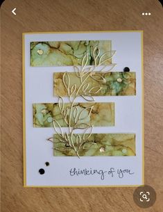 a close up of a card on a wooden table with writing in the middle that says thinking of you