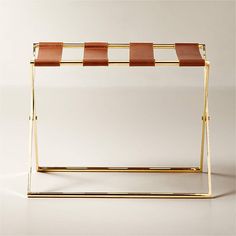 a gold and brown table with a striped shelf in the middle, on a white background