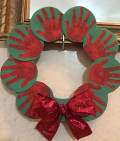 a handprinted wreath with red and green paint on it, sitting in front of a mirror