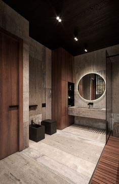 a large bathroom with wooden walls and flooring is lit by round mirrors on the wall