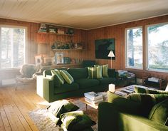 a living room filled with green couches and pillows on top of a hard wood floor