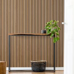 a potted plant sitting on top of a wooden shelf next to a black basket