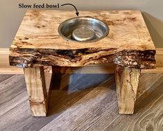 a wooden table with a metal bowl on it and the words slow feed bowl below