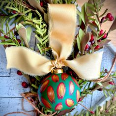 a christmas ornament with a bow on top of some branches and other decorations