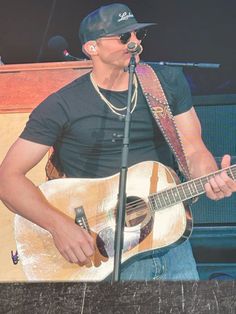 a man holding a guitar and singing into a microphone