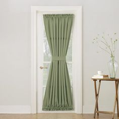 an open door with a green curtain in front of it and a small table next to it