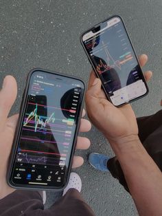 two people holding cell phones in their hands, one is showing the screen and the other has an upward graph on it