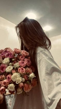 a woman holding a bouquet of flowers in her hand and looking down at the ground