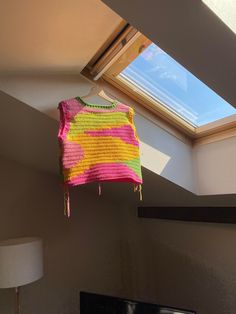 a pink and yellow sweater hanging from a window